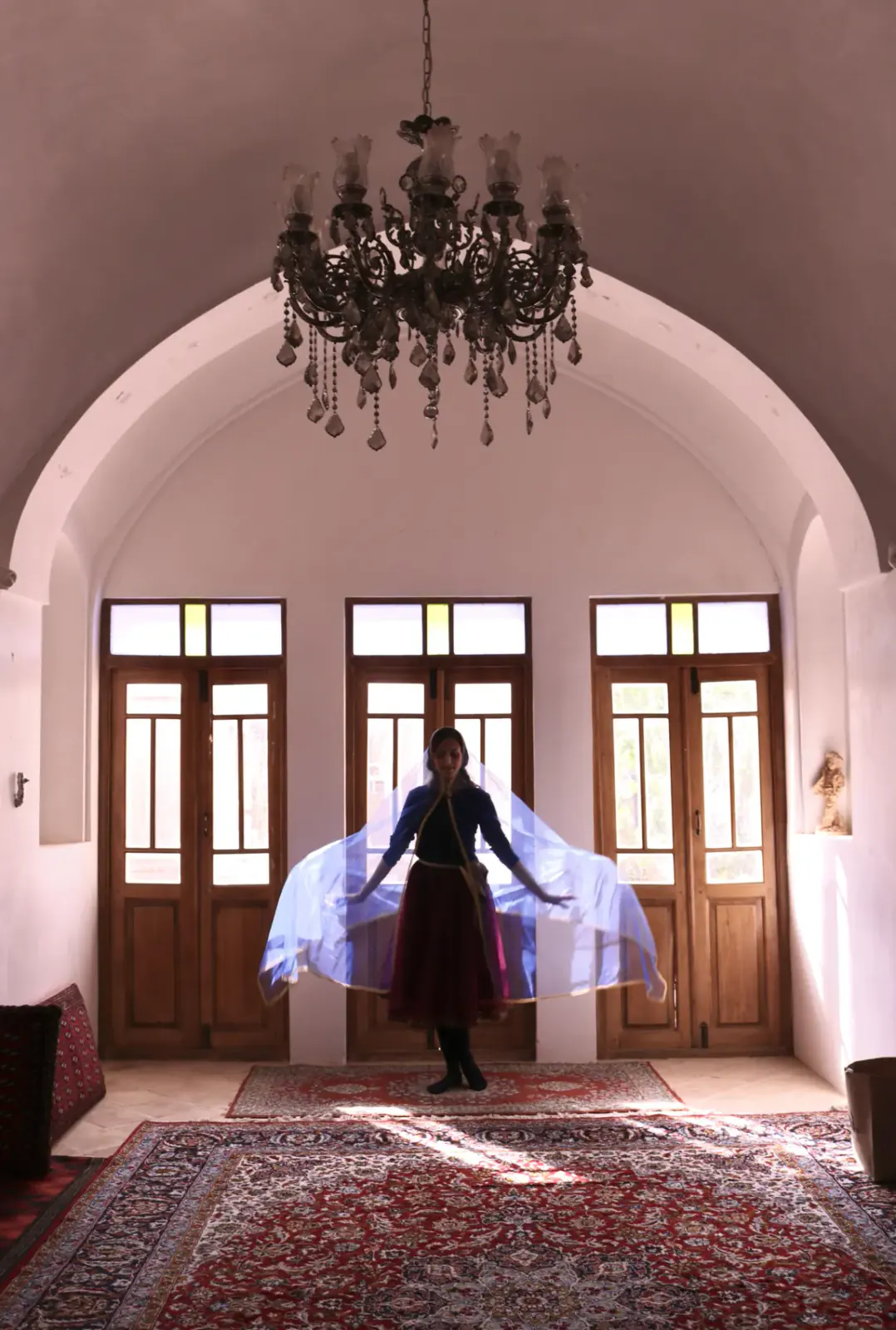 A Miniature dancer in costume beneath an arched ceiling and chandelier